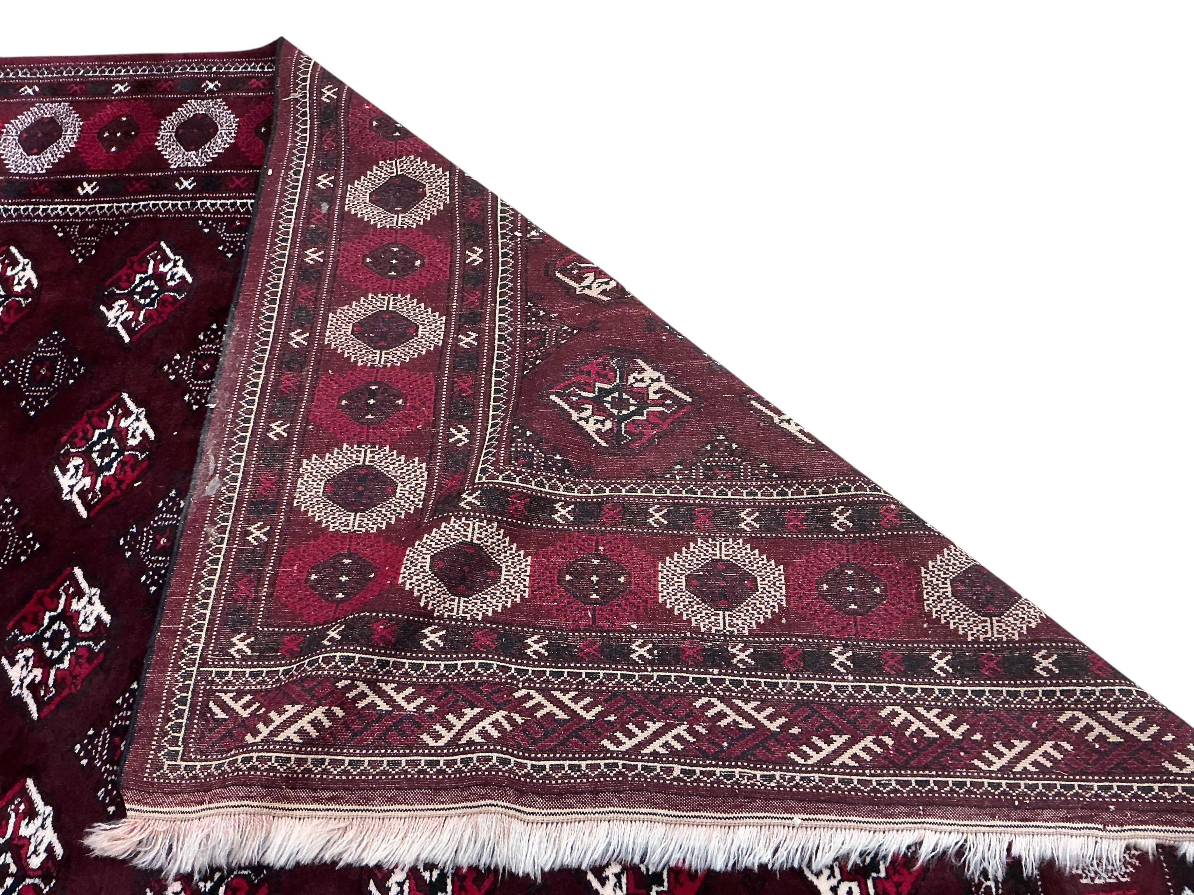 A Turkoman burgundy ground carpet, 386 x 234cm